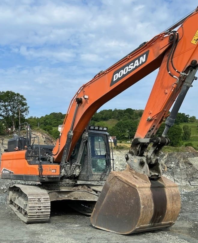 Excavadora Doosan naranja con orugas trabajando en una obra al aire libre