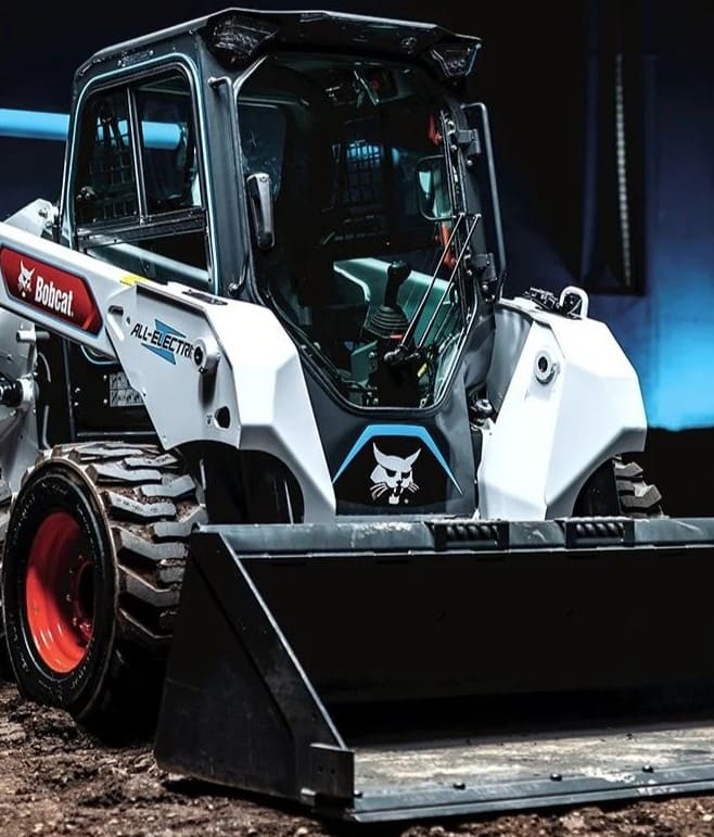 Minicargador eléctrico Bobcat con diseño moderno y estructura compacta, equipado con una pala frontal y neumáticos resistentes, ideal para trabajos en construcción y movimiento de materiales.